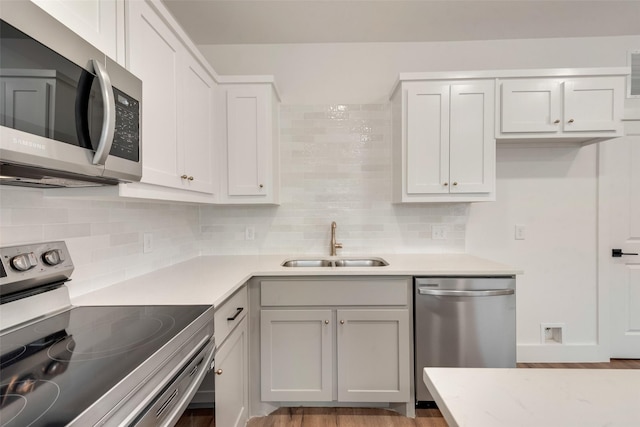 kitchen with tasteful backsplash, stainless steel appliances, sink, and white cabinets