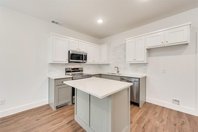 kitchen featuring tasteful backsplash, appliances with stainless steel finishes, a kitchen island, and light hardwood / wood-style flooring