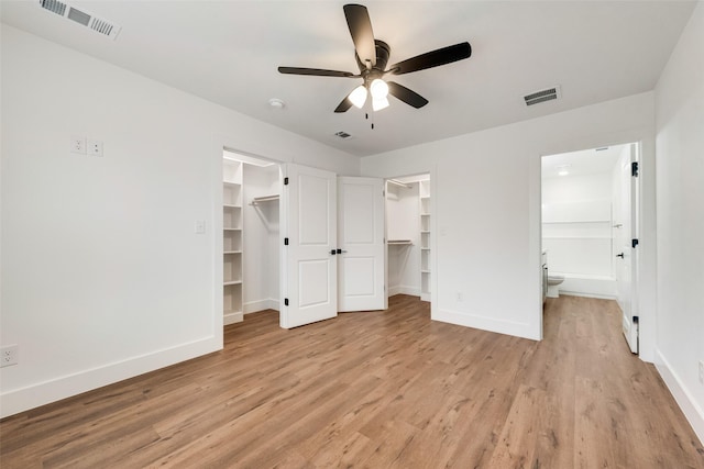 unfurnished bedroom with ensuite bath, a spacious closet, a closet, ceiling fan, and light hardwood / wood-style floors