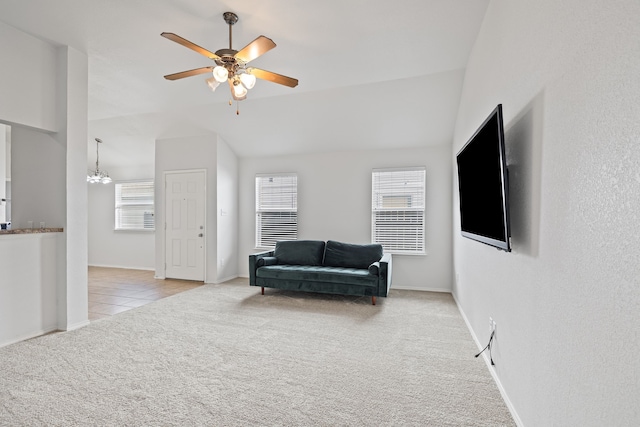 sitting room featuring vaulted ceiling, ceiling fan with notable chandelier, and light colored carpet