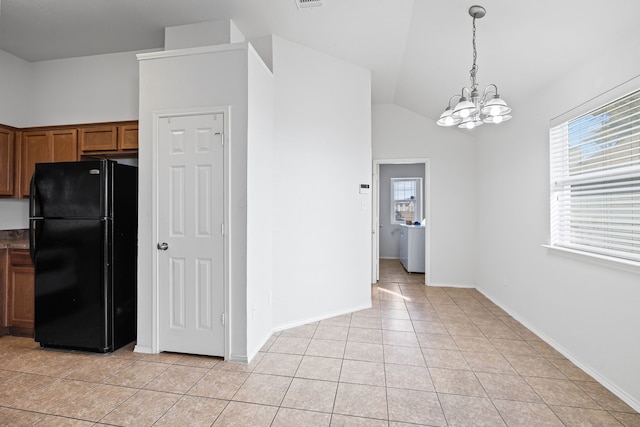 kitchen with black refrigerator, plenty of natural light, decorative light fixtures, and light tile patterned flooring