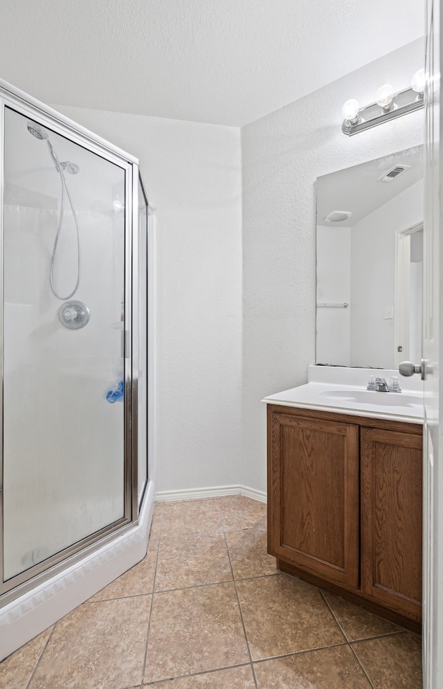 bathroom featuring tile patterned flooring, vanity, a shower with door, and a textured ceiling