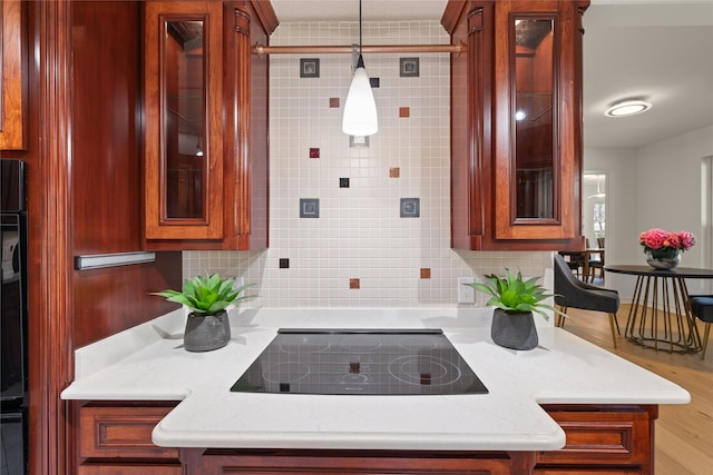 kitchen with pendant lighting, light stone counters, tasteful backsplash, and black electric cooktop