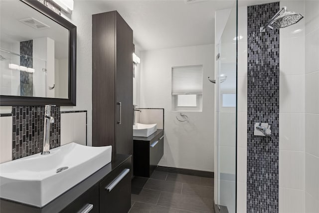 bathroom with tile patterned flooring, vanity, a tile shower, and decorative backsplash