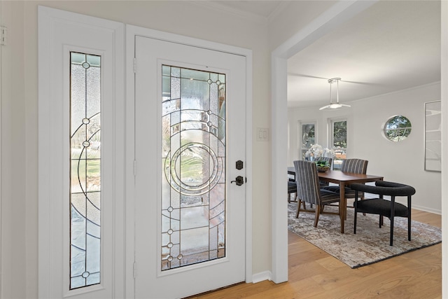 entryway with ornamental molding and hardwood / wood-style floors