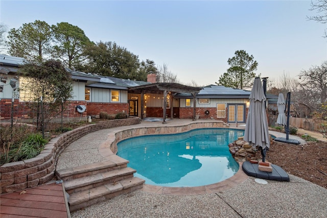 pool at dusk with a patio area