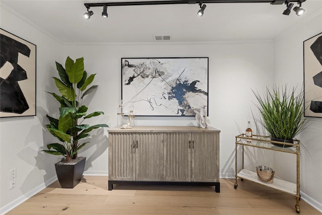 interior space with crown molding, rail lighting, and light hardwood / wood-style floors