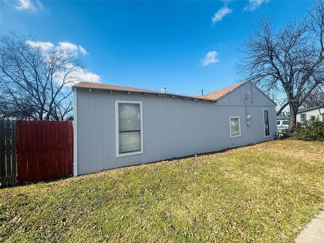 view of home's exterior with a lawn and fence