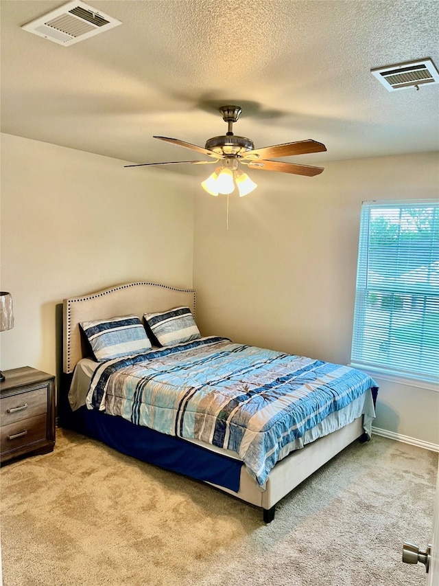 bedroom with a textured ceiling, light colored carpet, and ceiling fan