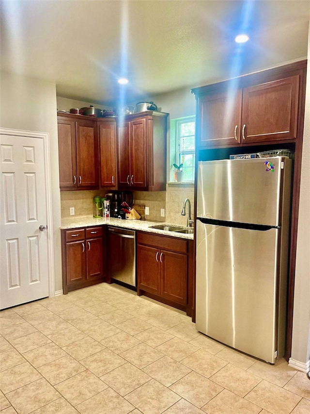 kitchen with light stone counters, sink, backsplash, and stainless steel appliances