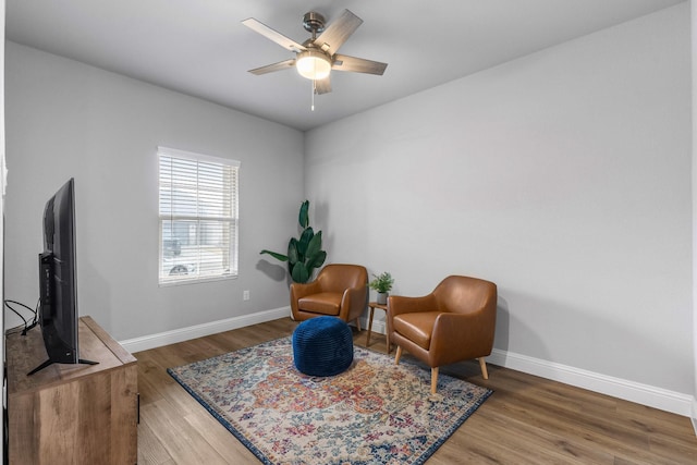 sitting room with a ceiling fan, baseboards, and wood finished floors