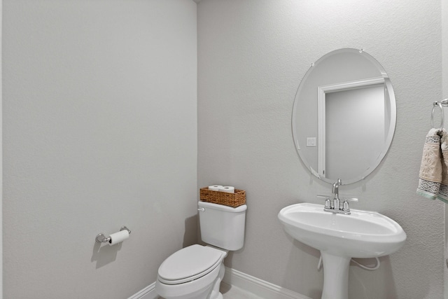 bathroom featuring baseboards and toilet