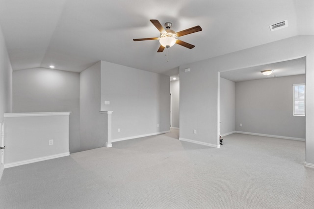 carpeted spare room featuring visible vents, lofted ceiling, baseboards, and ceiling fan