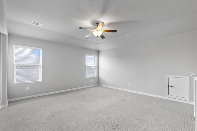 carpeted empty room with visible vents, baseboards, and a ceiling fan