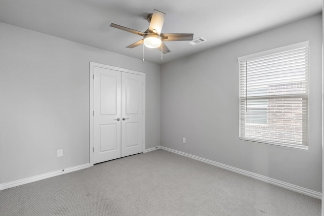 unfurnished bedroom featuring a ceiling fan, visible vents, baseboards, a closet, and light colored carpet