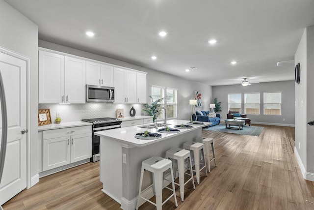 kitchen with white cabinetry, appliances with stainless steel finishes, a breakfast bar area, and a center island with sink