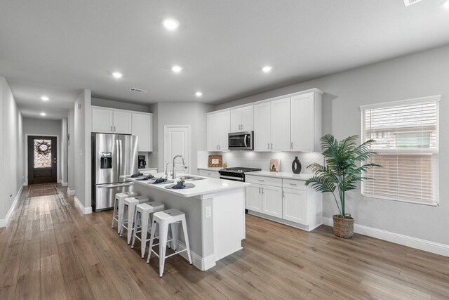 kitchen featuring white cabinetry, sink, a center island with sink, and appliances with stainless steel finishes