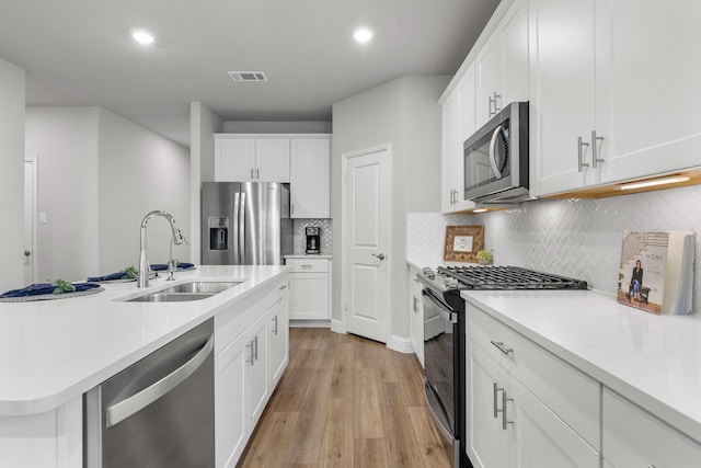 kitchen featuring sink, stainless steel appliances, an island with sink, and white cabinets