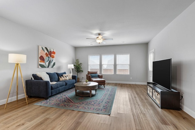 living room featuring ceiling fan, baseboards, and wood finished floors