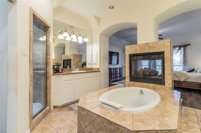 bathroom with a tiled fireplace, vanity, tile patterned floors, and shower with separate bathtub