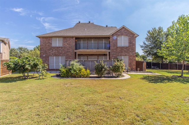 rear view of house featuring a yard and a balcony