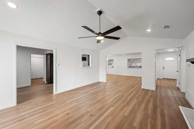 unfurnished living room with lofted ceiling, a textured ceiling, ceiling fan, and light hardwood / wood-style flooring