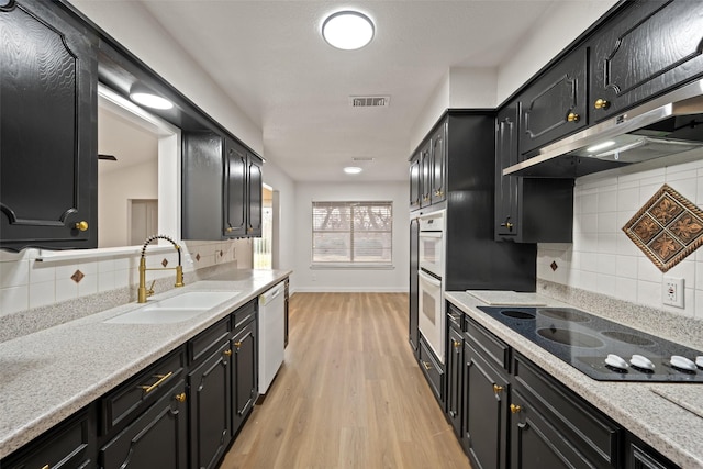 kitchen featuring sink, white appliances, light hardwood / wood-style floors, and light stone countertops