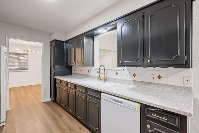 kitchen featuring sink, white appliances, light hardwood / wood-style floors, and backsplash