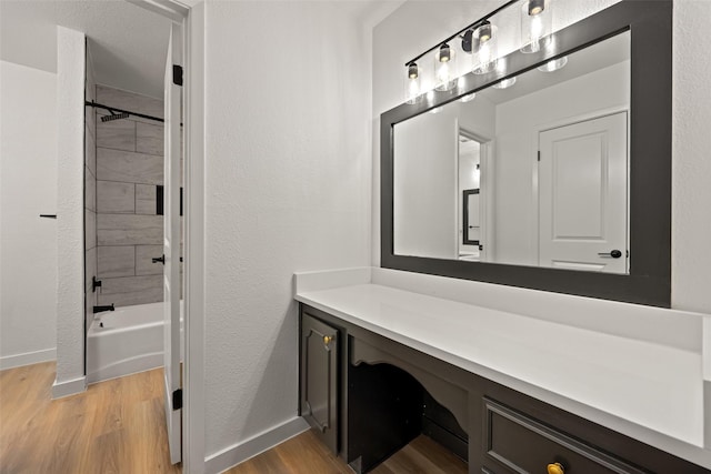 bathroom with wood-type flooring, tiled shower / bath combo, and vanity