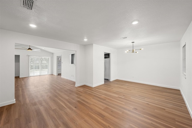 unfurnished living room featuring ceiling fan with notable chandelier, hardwood / wood-style floors, and a textured ceiling