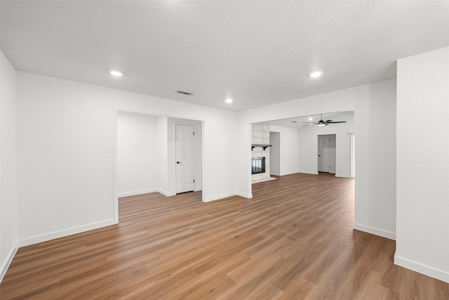 unfurnished living room with hardwood / wood-style flooring, a textured ceiling, and ceiling fan