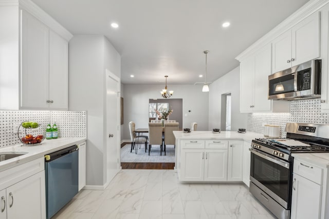 kitchen featuring white cabinetry, appliances with stainless steel finishes, decorative light fixtures, and kitchen peninsula