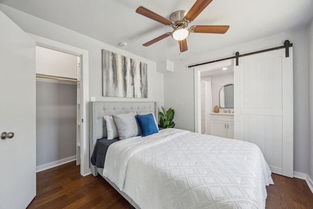 bedroom featuring dark hardwood / wood-style floors, ceiling fan, a barn door, and ensuite bath