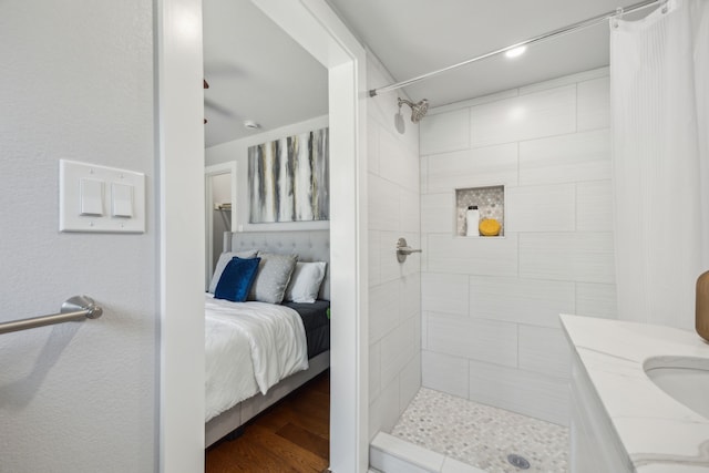 bathroom with a tile shower, vanity, and hardwood / wood-style flooring