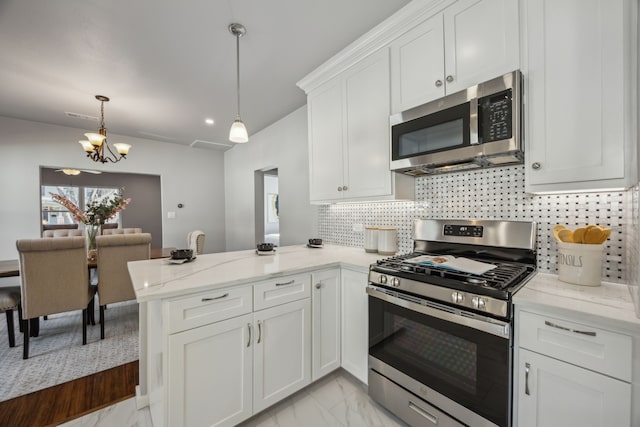 kitchen with appliances with stainless steel finishes, hanging light fixtures, light stone counters, white cabinets, and kitchen peninsula