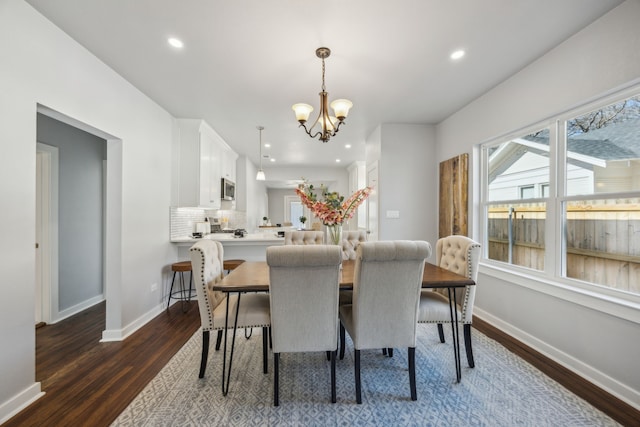 dining room with dark hardwood / wood-style flooring and an inviting chandelier