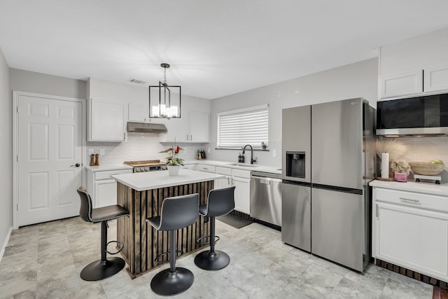 kitchen with sink, white cabinetry, a center island, appliances with stainless steel finishes, and pendant lighting