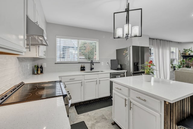 kitchen with sink, appliances with stainless steel finishes, white cabinetry, hanging light fixtures, and tasteful backsplash