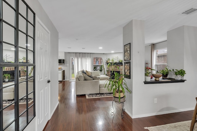 living room featuring dark hardwood / wood-style flooring and a brick fireplace