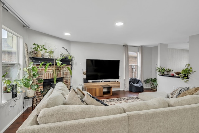 living room featuring plenty of natural light, dark hardwood / wood-style floors, and a brick fireplace