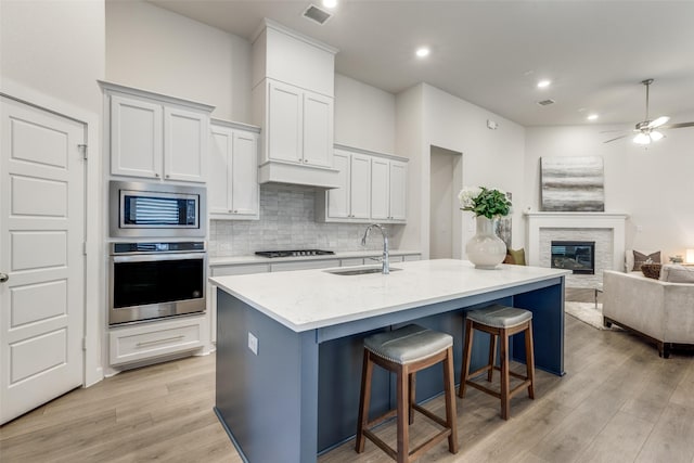 kitchen featuring appliances with stainless steel finishes, a breakfast bar, a center island with sink, and sink