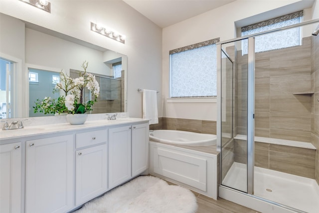 bathroom featuring independent shower and bath, vanity, and plenty of natural light