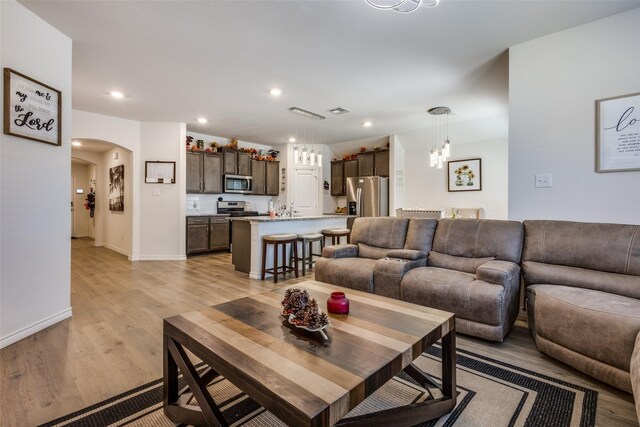 kitchen featuring dark brown cabinets, appliances with stainless steel finishes, a center island with sink, and light wood-type flooring