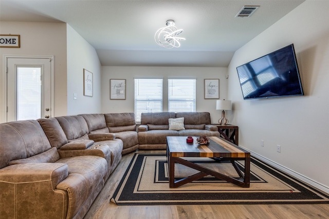 living area featuring vaulted ceiling, wood finished floors, visible vents, and baseboards