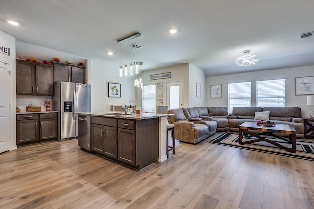 kitchen featuring appliances with stainless steel finishes, open floor plan, visible vents, and a sink