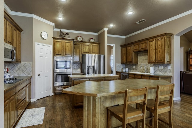 kitchen with sink, crown molding, a center island, appliances with stainless steel finishes, and dark hardwood / wood-style floors