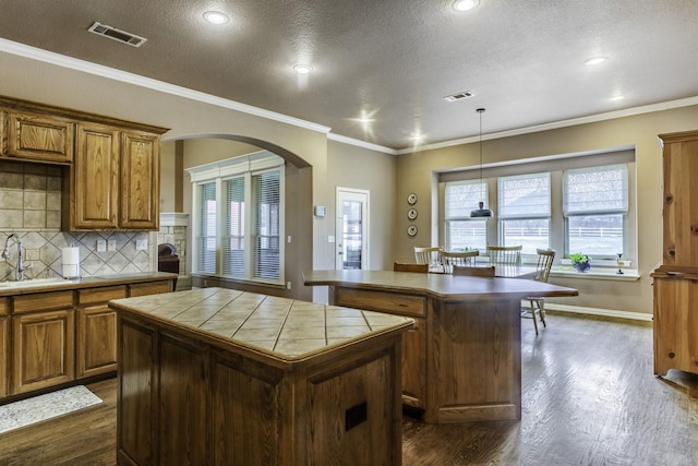 kitchen featuring dark hardwood / wood-style flooring, backsplash, tile countertops, and a kitchen island