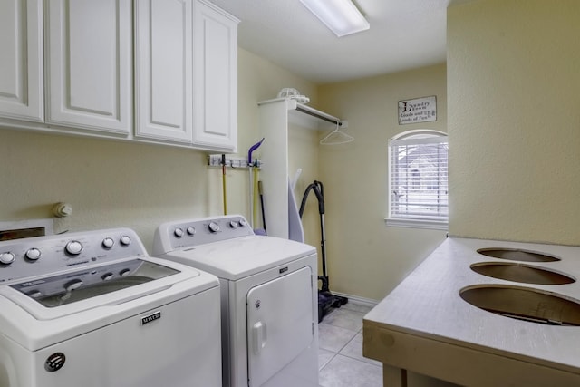 laundry room featuring cabinets, light tile patterned flooring, and washer and clothes dryer