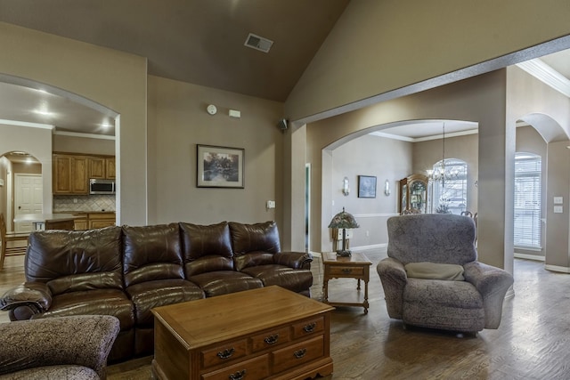 living room featuring lofted ceiling, a notable chandelier, crown molding, and dark wood-type flooring