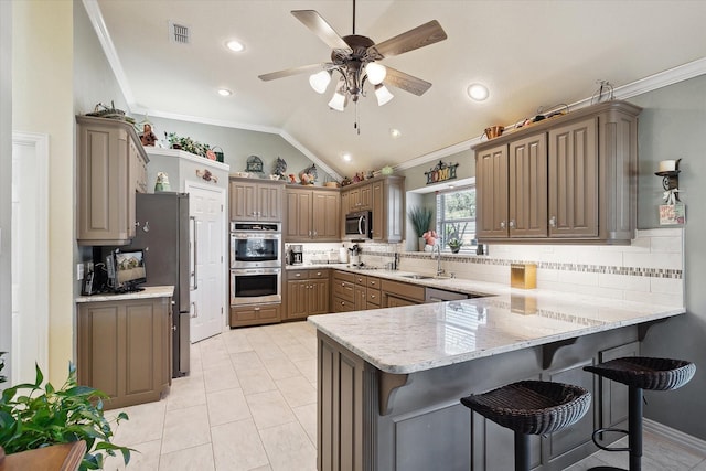 kitchen featuring ornamental molding, a kitchen breakfast bar, kitchen peninsula, and appliances with stainless steel finishes